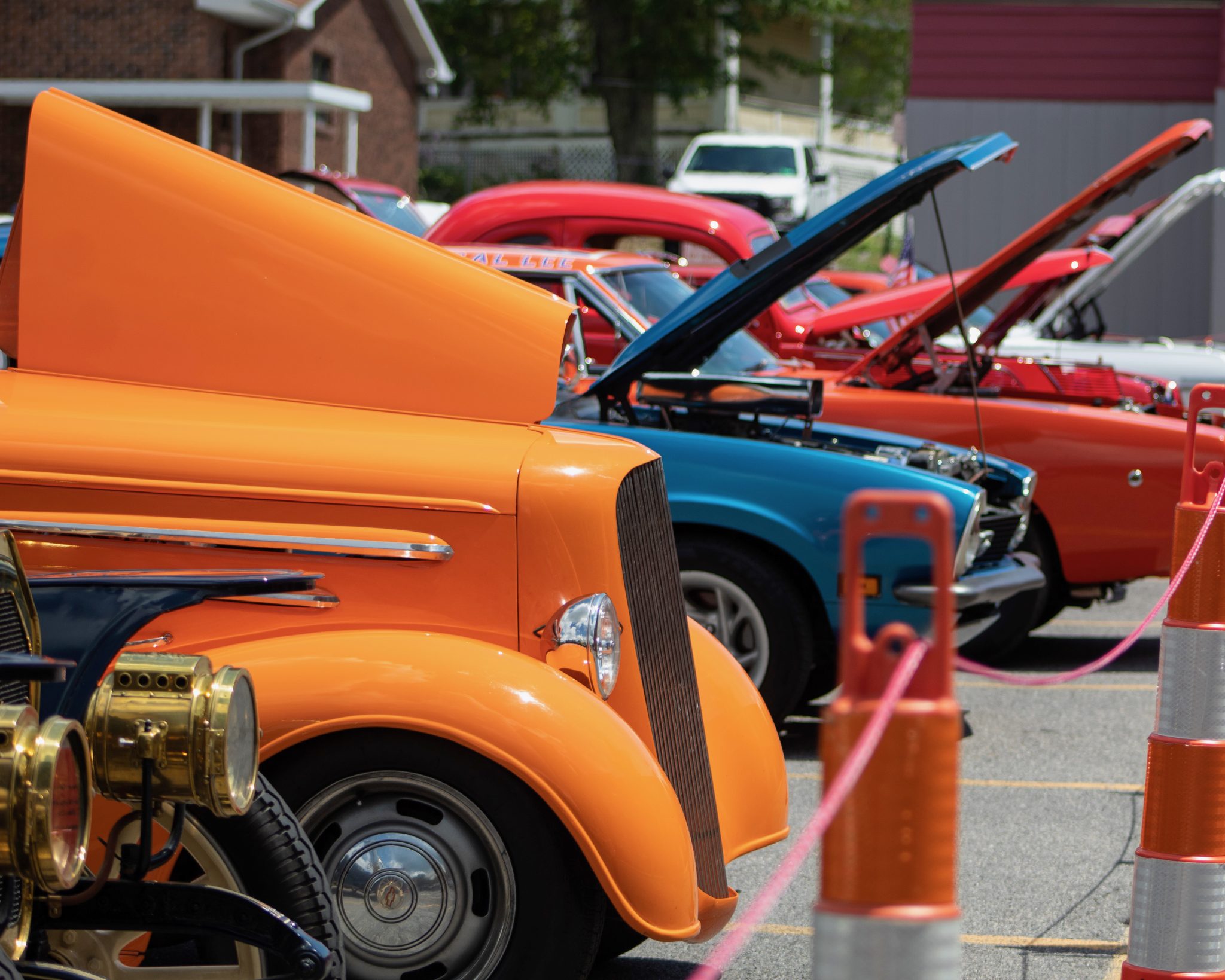A row of classic hot rods with their hoods popped at a car show